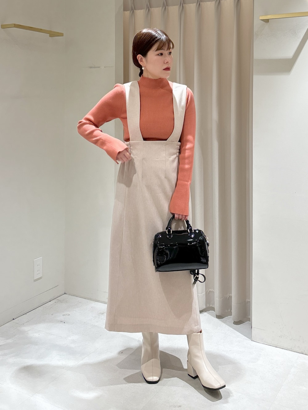 ピンク系のニット/セーター、ベージュ系のジャンパースカート、ブラック系のショルダーバッグを着用したレディースの冬コーディネートの5枚目の写真