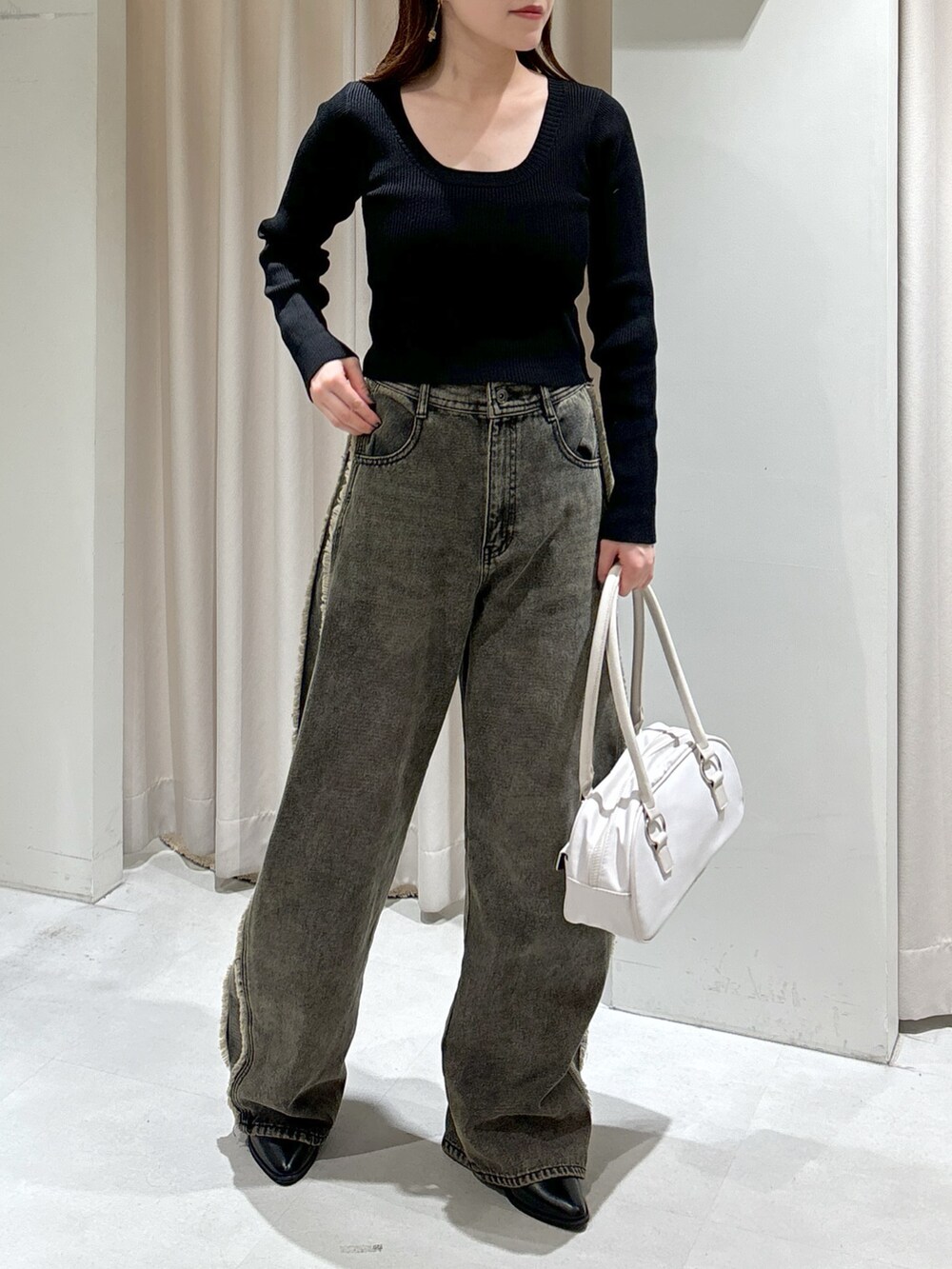 ブラウン系のチェスターコート、ブラック系のニット/セーター、ホワイト系のトートバッグを着用したレディースの秋コーディネートの6枚目の写真