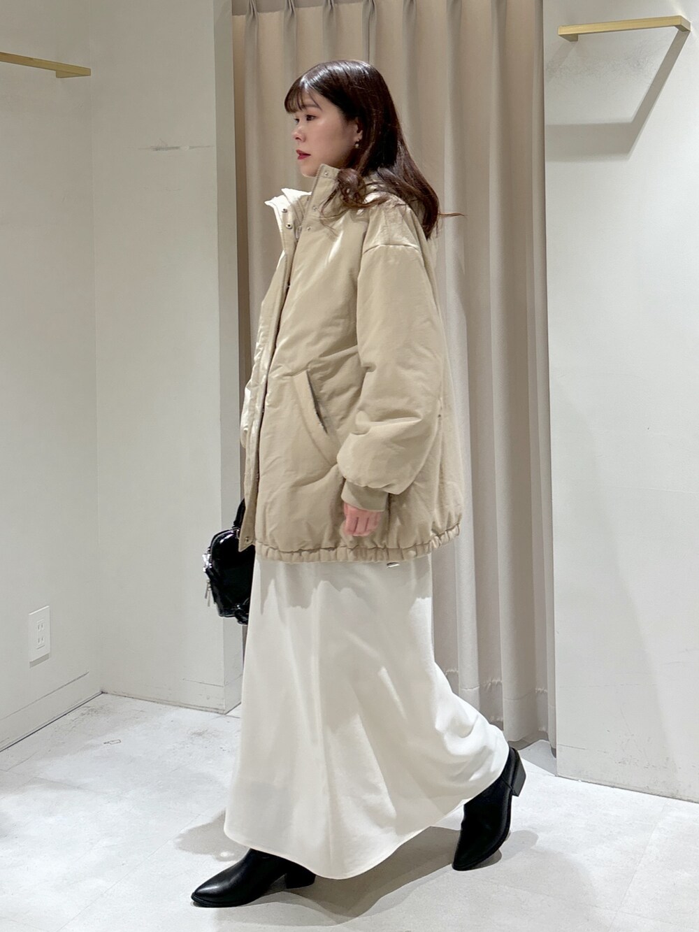 ベージュ系のブルゾン、ブラック系のショルダーバッグ、ホワイト系のスカートを着用したレディースの冬コーディネートの3枚目の写真