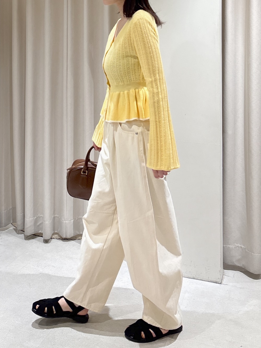 イエロー系のニット/セーター、ホワイト系のその他パンツ、ブラウン系のハンドバッグを着用したレディースの春コーディネートの3枚目の写真
