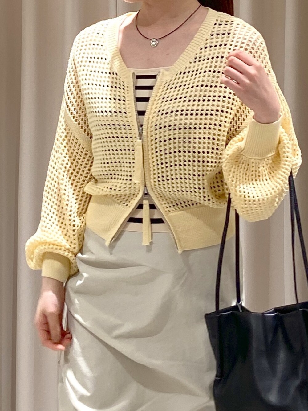 イエロー系のカーディガン/ボレロ、ホワイト系のタンクトップ、ベージュ系のスカートを着用したレディースの春コーディネートの3枚目の写真