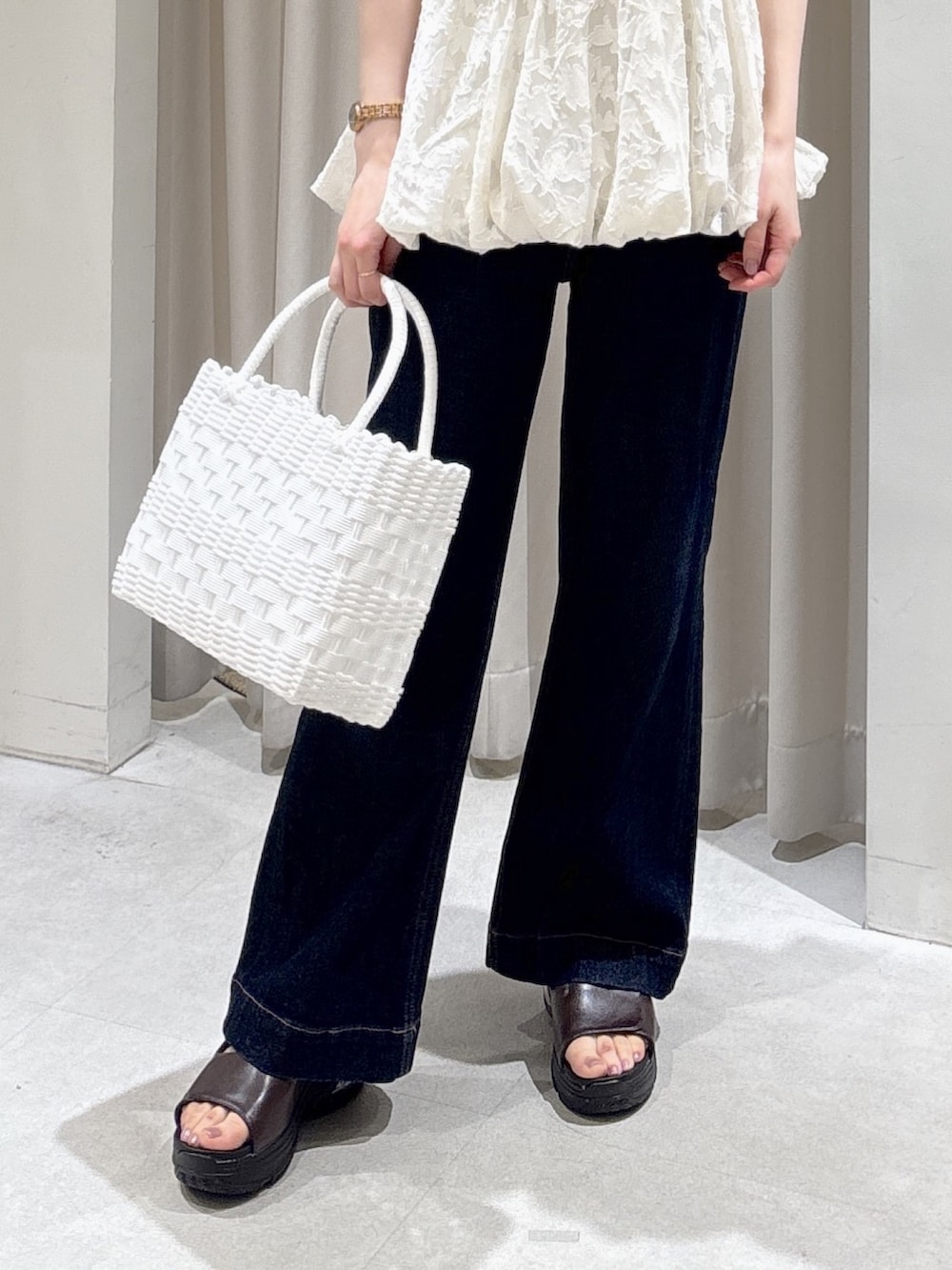 ホワイト系のニット/セーター、ホワイト系のトートバッグ、ブルー系のデニムパンツを着用したレディースの春コーディネートの6枚目の写真
