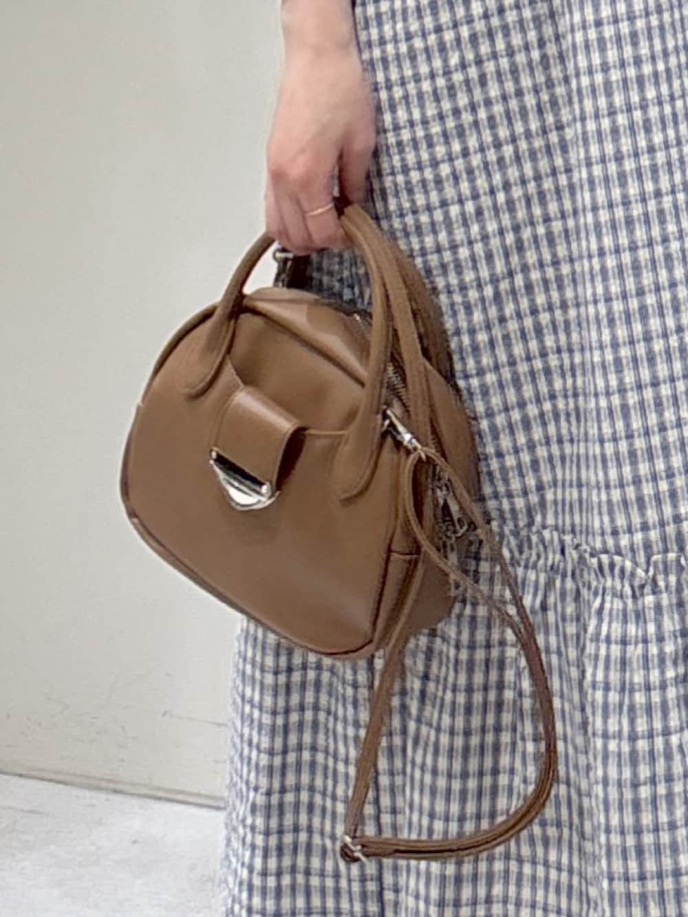 ブラック系のワンピース、ブラウン系のハンドバッグ、ブラック系のサンダルを着用したレディースの春コーディネートの5枚目の写真