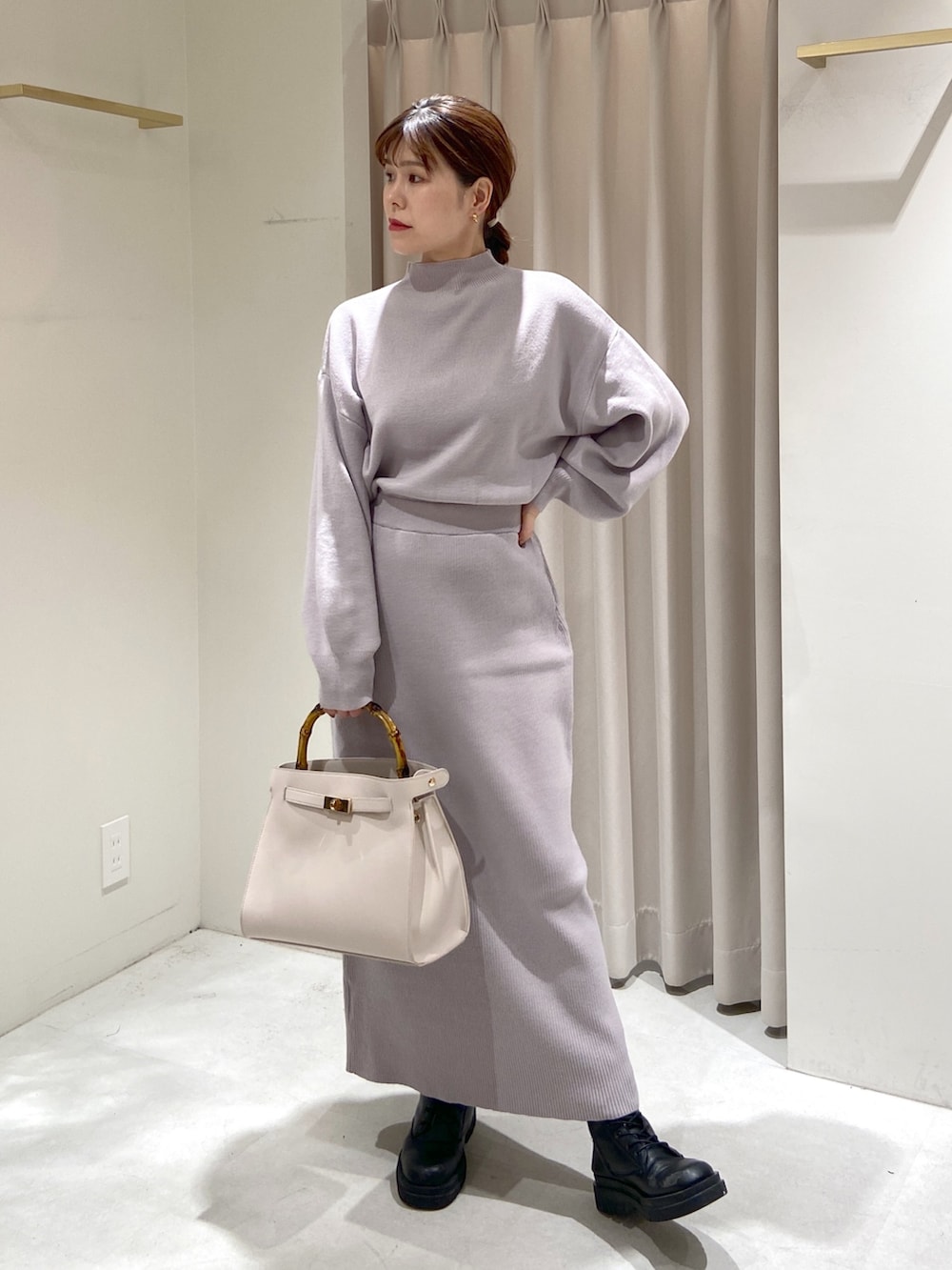 パープル系のワンピース、ホワイト系のショルダーバッグ、ブラック系のブーツを着用したレディースの冬コーディネートの3枚目の写真