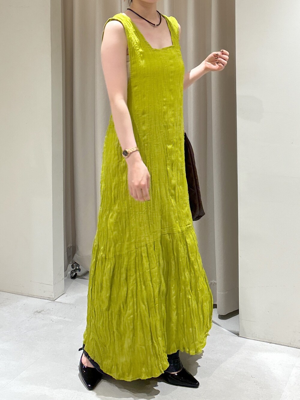 グリーン系のワンピース、ブラウン系のトートバッグ、ブラック系のデニムパンツを着用したレディースの秋コーディネートの3枚目の写真