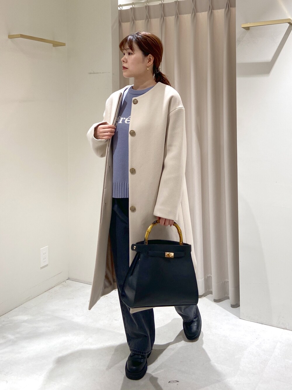 シルバー系のショルダーバッグ、ブラック系のデニムパンツ、ブラック系のブーツを着用したレディースの冬コーディネートの4枚目の写真