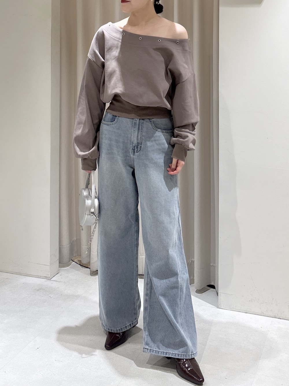 ブラウン系のスウェット、ブルー系のデニムパンツ、シルバー系のショルダーバッグを着用したレディースの冬コーディネートの2枚目の写真