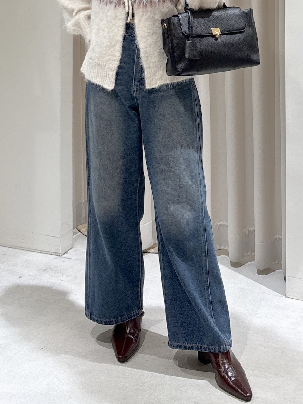 ホワイト系のニット/セーター、ブルー系のデニムパンツ、ブラウン系のパンプスを着用したレディースの秋コーディネートの4枚目の写真