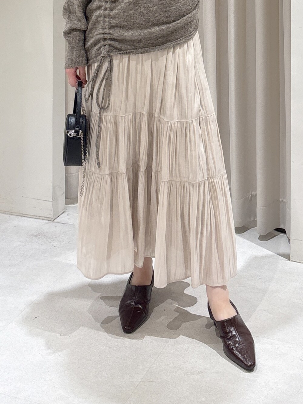 ブラウン系のニット/セーター、ホワイト系のスカート、ブラウン系のパンプスを着用したレディースの冬コーディネートの5枚目の写真