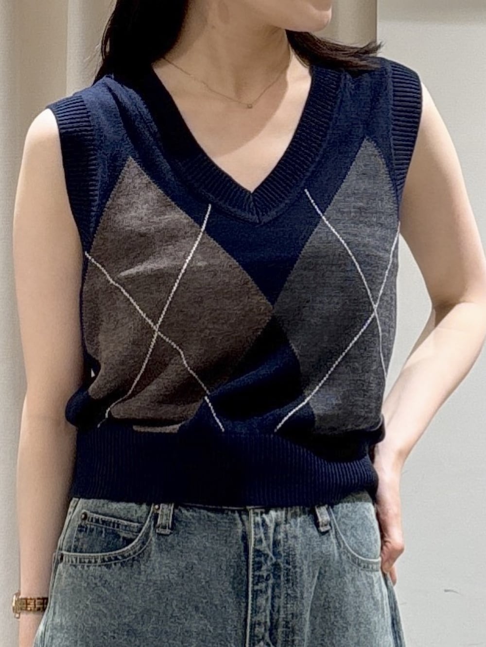 ブルー系のニット/セーター、ブルー系のデニムパンツ、ブラック系のショルダーバッグを着用したレディースの夏コーディネートの3枚目の写真