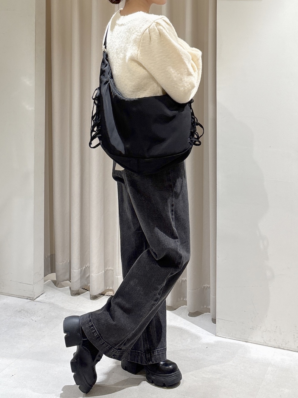 ホワイト系のニット/セーター、ブラック系のトートバッグ、ブラック系のブーツを着用したレディースの秋コーディネートの4枚目の写真