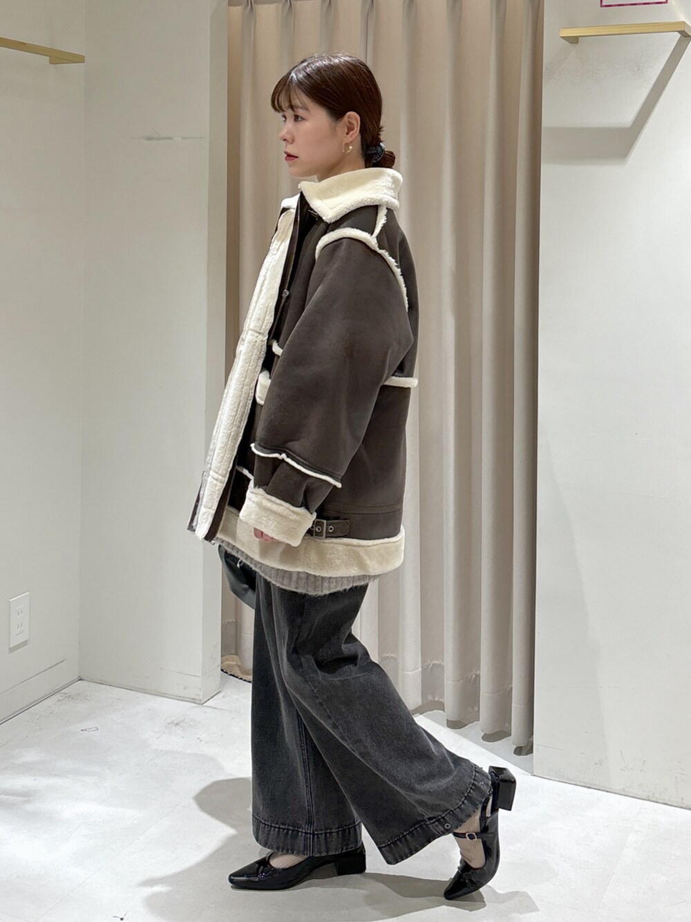 ブラウン系のブルゾン、ブラック系のデニムパンツ、ブラック系のハンドバッグを着用したレディースの秋コーディネートの3枚目の写真