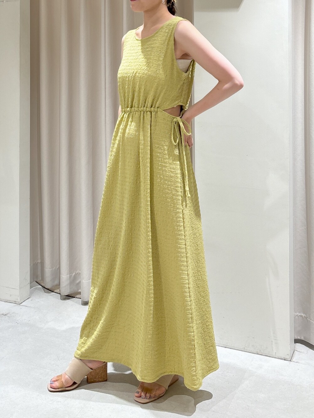 イエロー系のワンピース、ブラック系のショルダーバッグ、グレー系のサンダルを着用したレディースの夏コーディネートの2枚目の写真