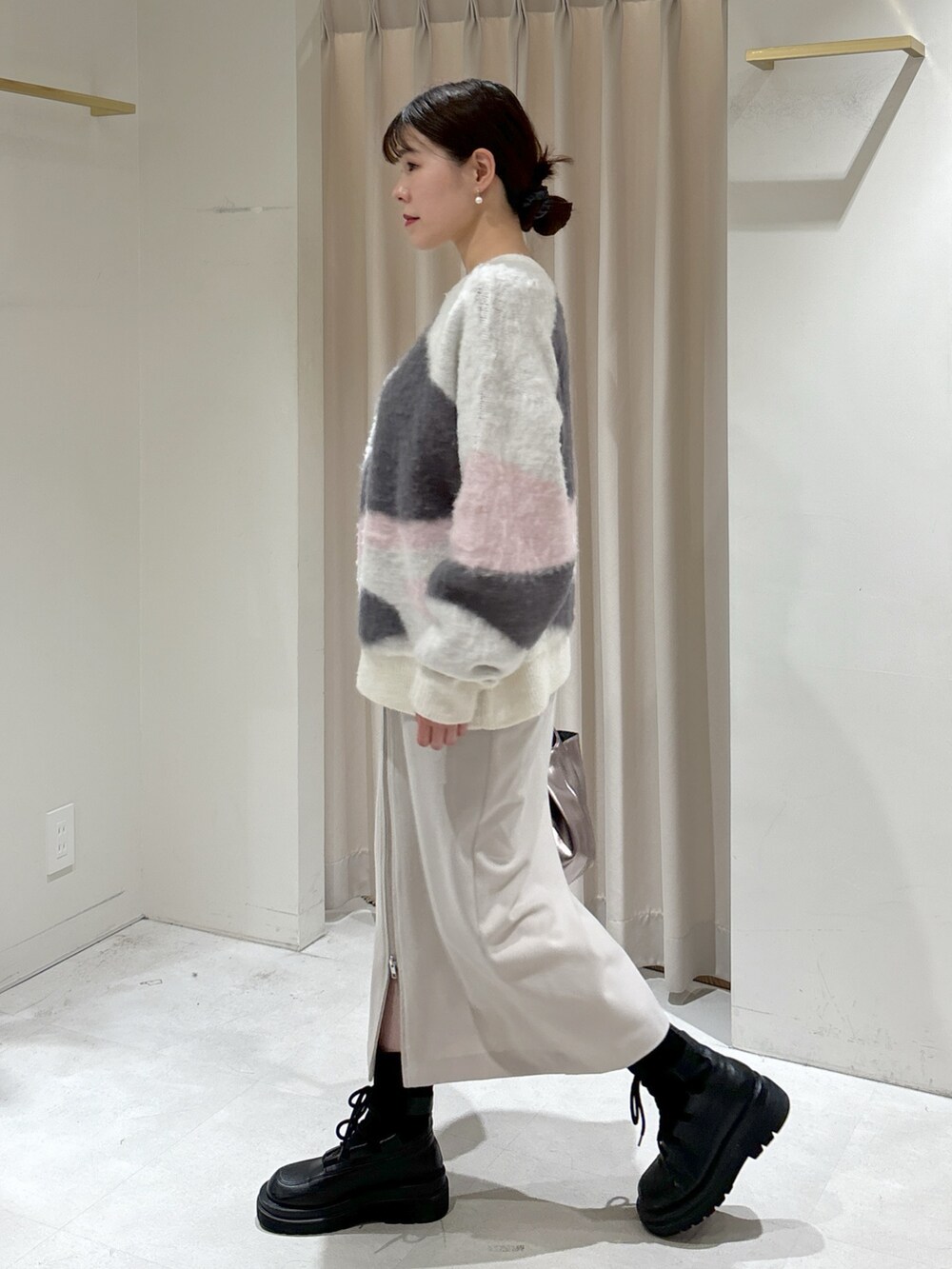 ホワイト系のニット/セーター、グレー系のスカート、シルバー系のハンドバッグを着用したレディースの冬コーディネートの3枚目の写真