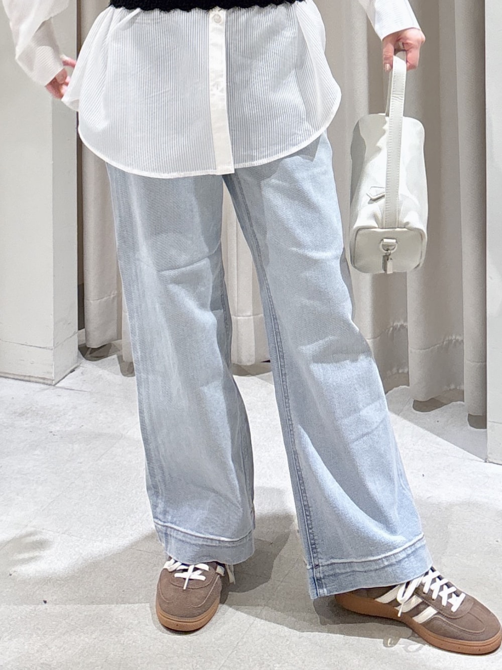 ホワイト系のシャツ/ブラウス、ブラック系のニット/セーター、ブルー系のデニムパンツを着用したレディースの春コーディネートの4枚目の写真