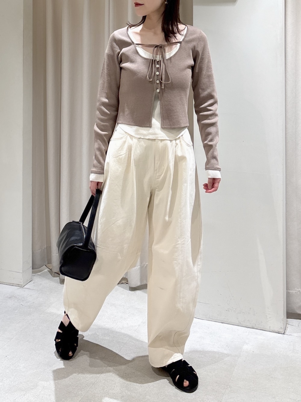 ブラウン系のニット/セーター、ホワイト系のその他パンツ、ブラック系のサンダルを着用したレディースの春コーディネートの3枚目の写真