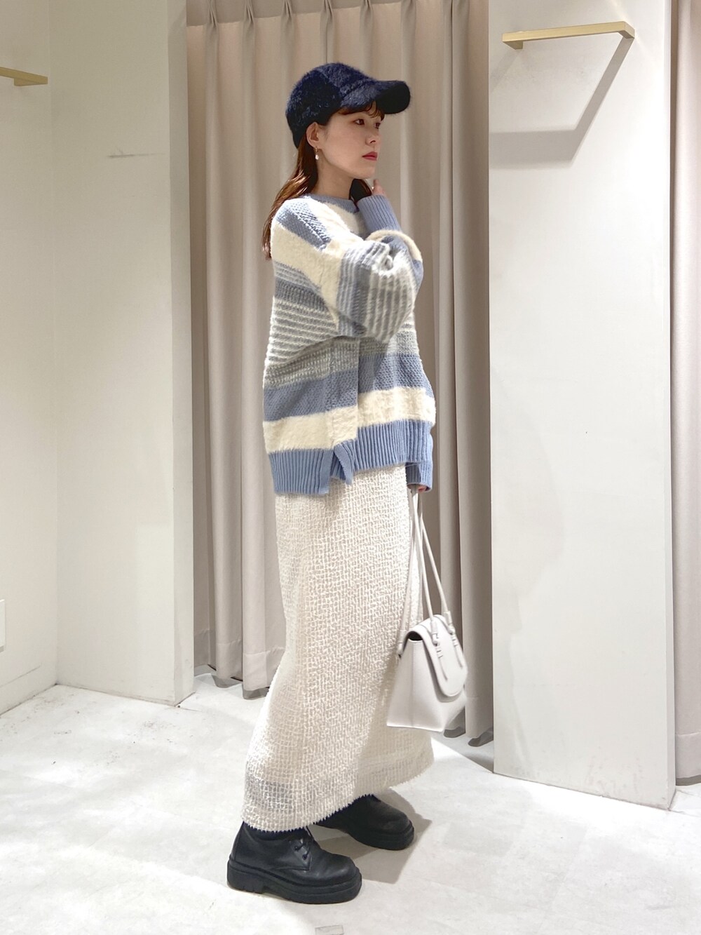 ブルー系のニット/セーター、ホワイト系のスカート、ブラック系のブーツを着用したレディースの冬コーディネートの3枚目の写真