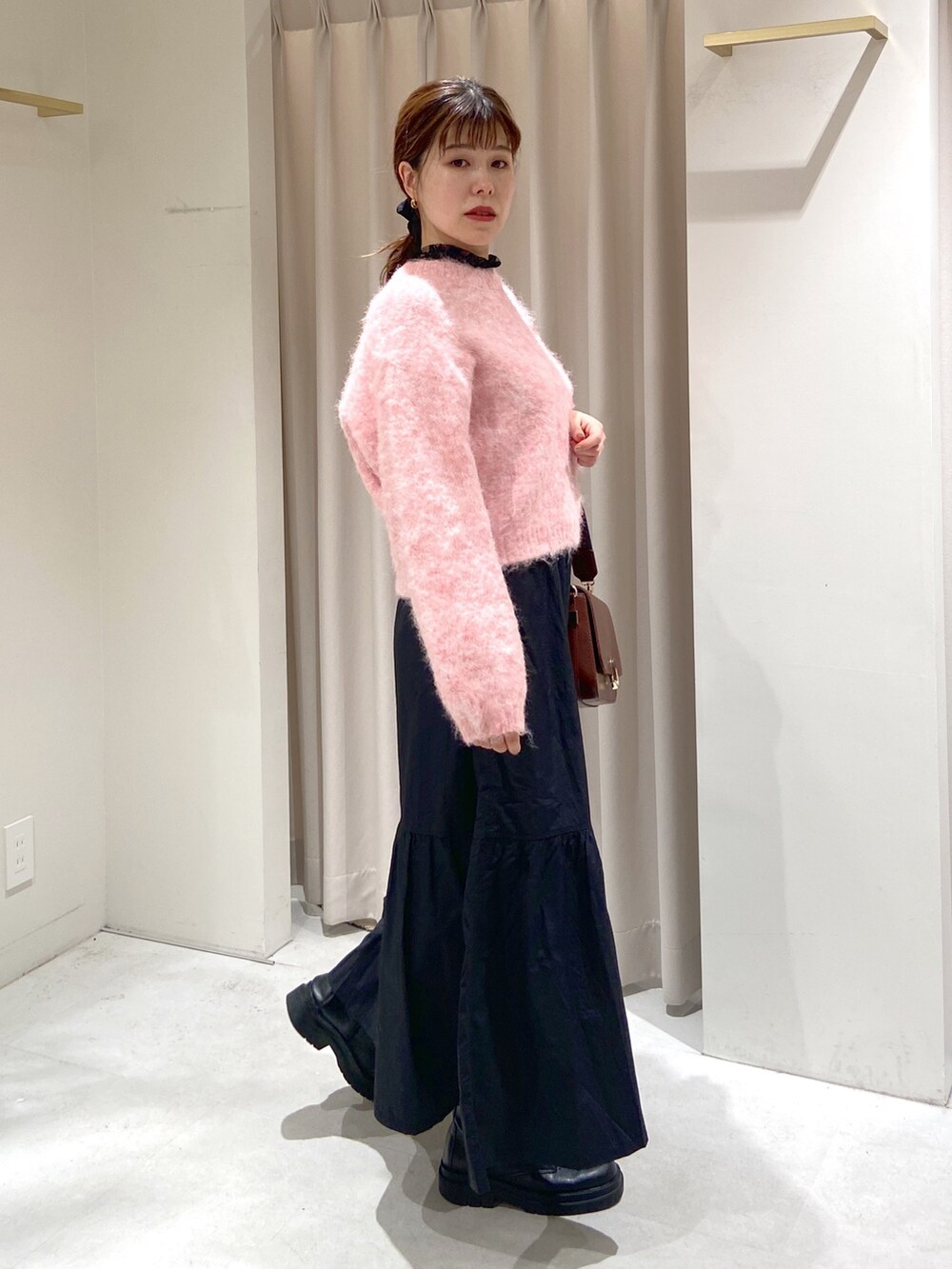 ブラック系のスカート、ブラウン系のショルダーバッグ、ブラック系のブーツを着用したレディースの冬コーディネートの3枚目の写真