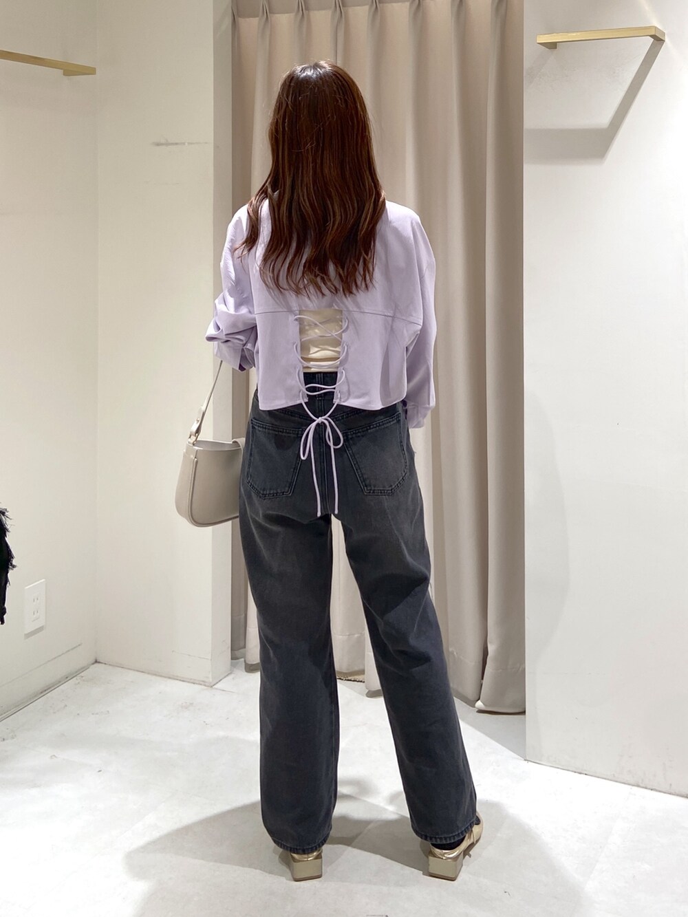 ブラック系のデニムパンツ、ゴールド系のパンプス、グレー系のショルダーバッグを着用したレディースの春コーディネートの4枚目の写真