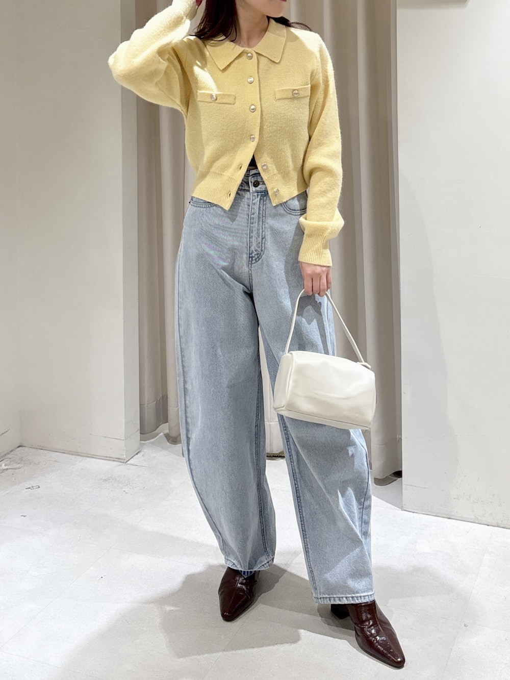 イエロー系のニット/セーター、ブラウン系のパンプス、ブルー系のデニムパンツを着用したレディースの冬コーディネートの2枚目の写真