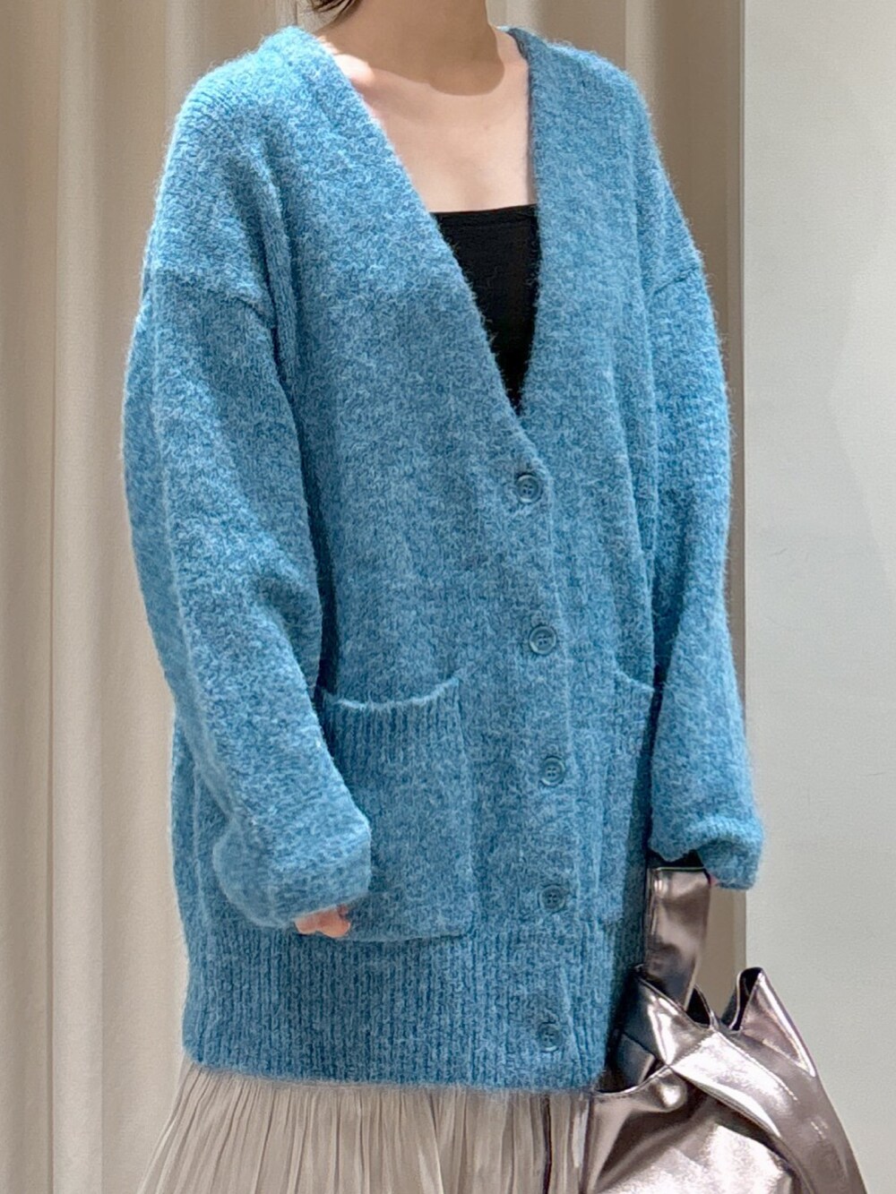 ブルー系のカーディガン/ボレロ、ブラック系のキャミソール、ホワイト系のスカートを着用したレディースの秋コーディネートの4枚目の写真