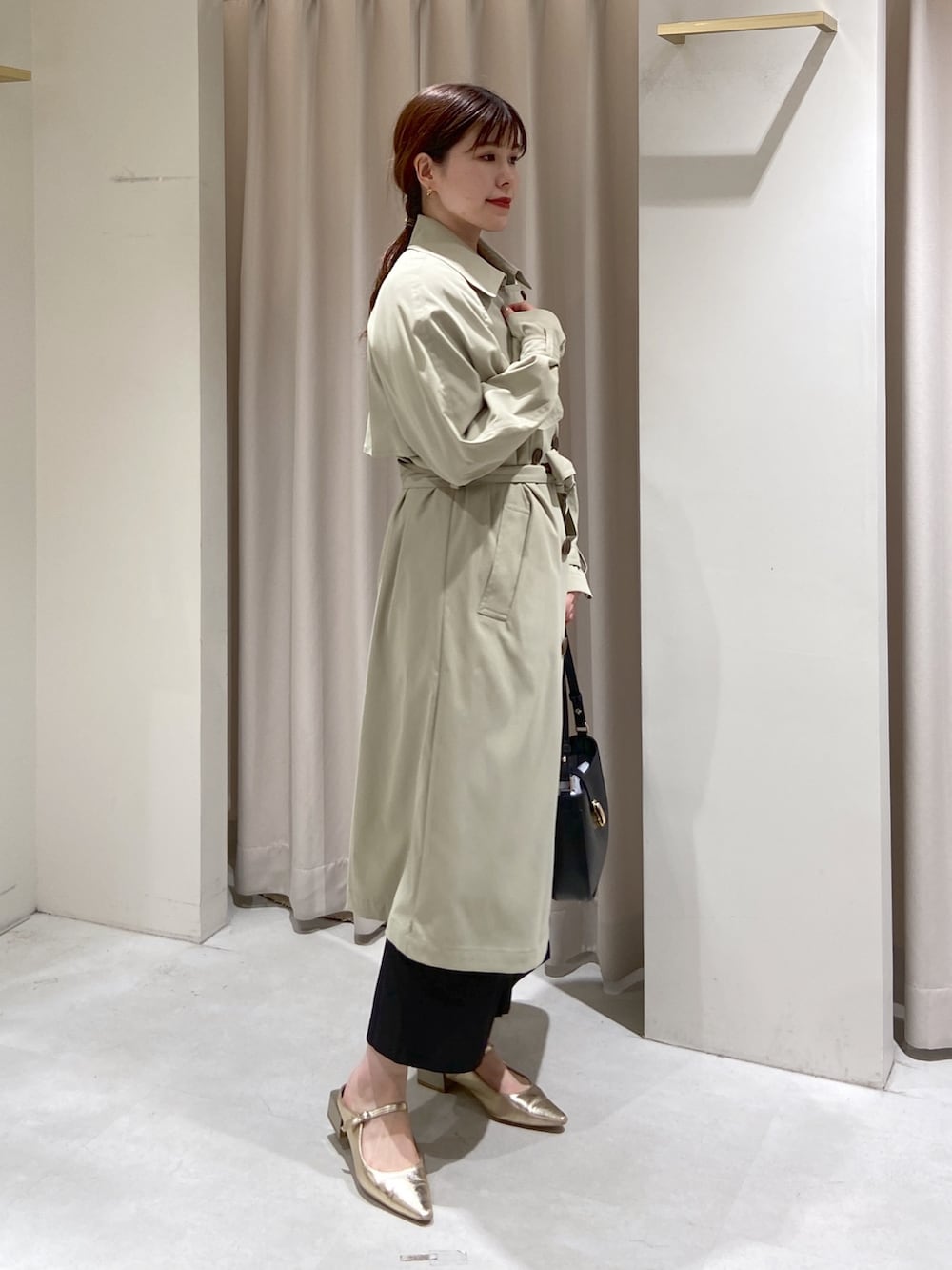 グリーン系のトレンチコート、ブラック系のショルダーバッグ、グリーン系のニット/セーターを着用したレディースの春コーディネートの3枚目の写真