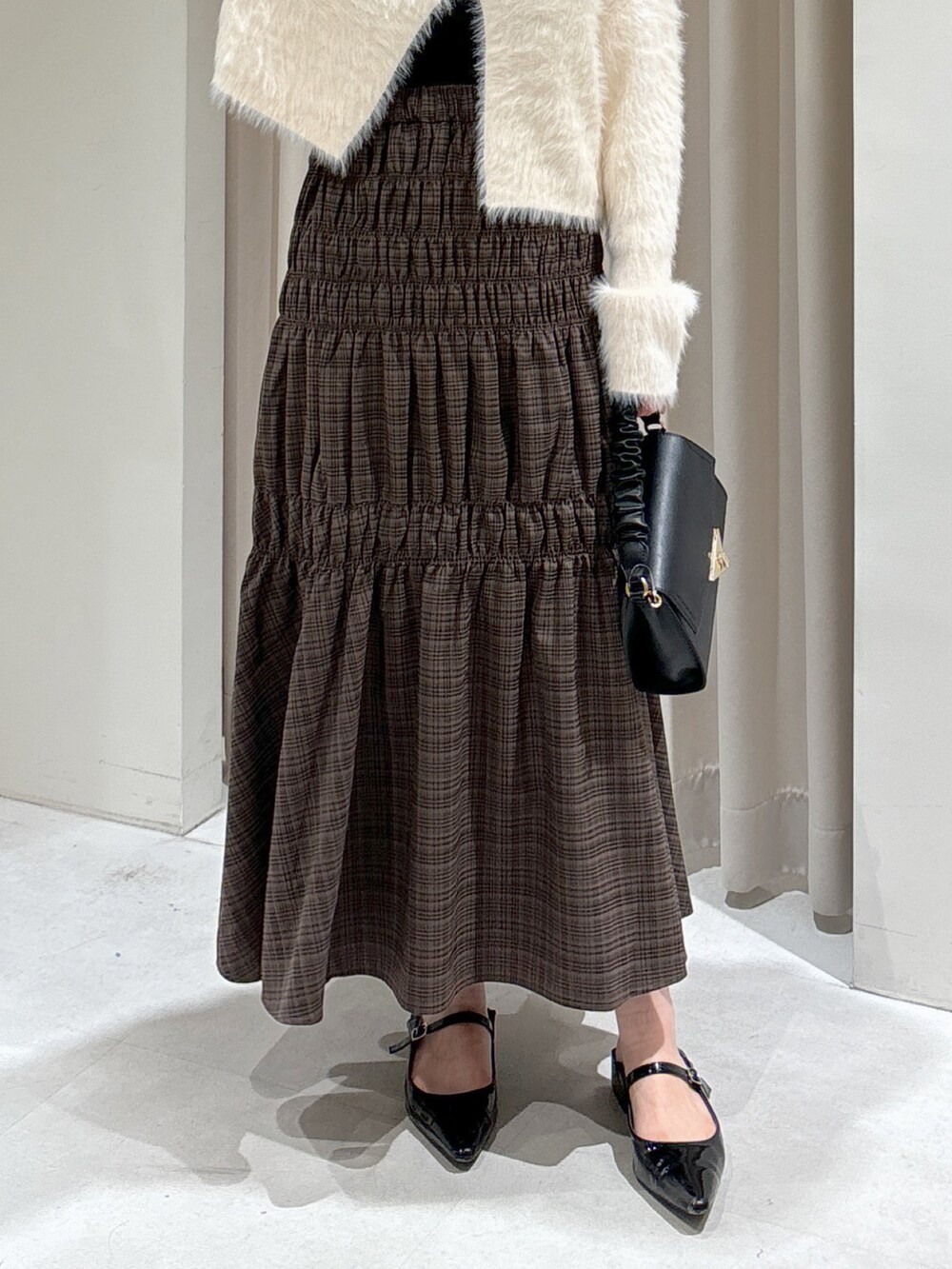 ホワイト系のカーディガン/ボレロ、ブラック系のキャミソール、ブラック系のショルダーバッグを着用したレディースの秋コーディネートの4枚目の写真