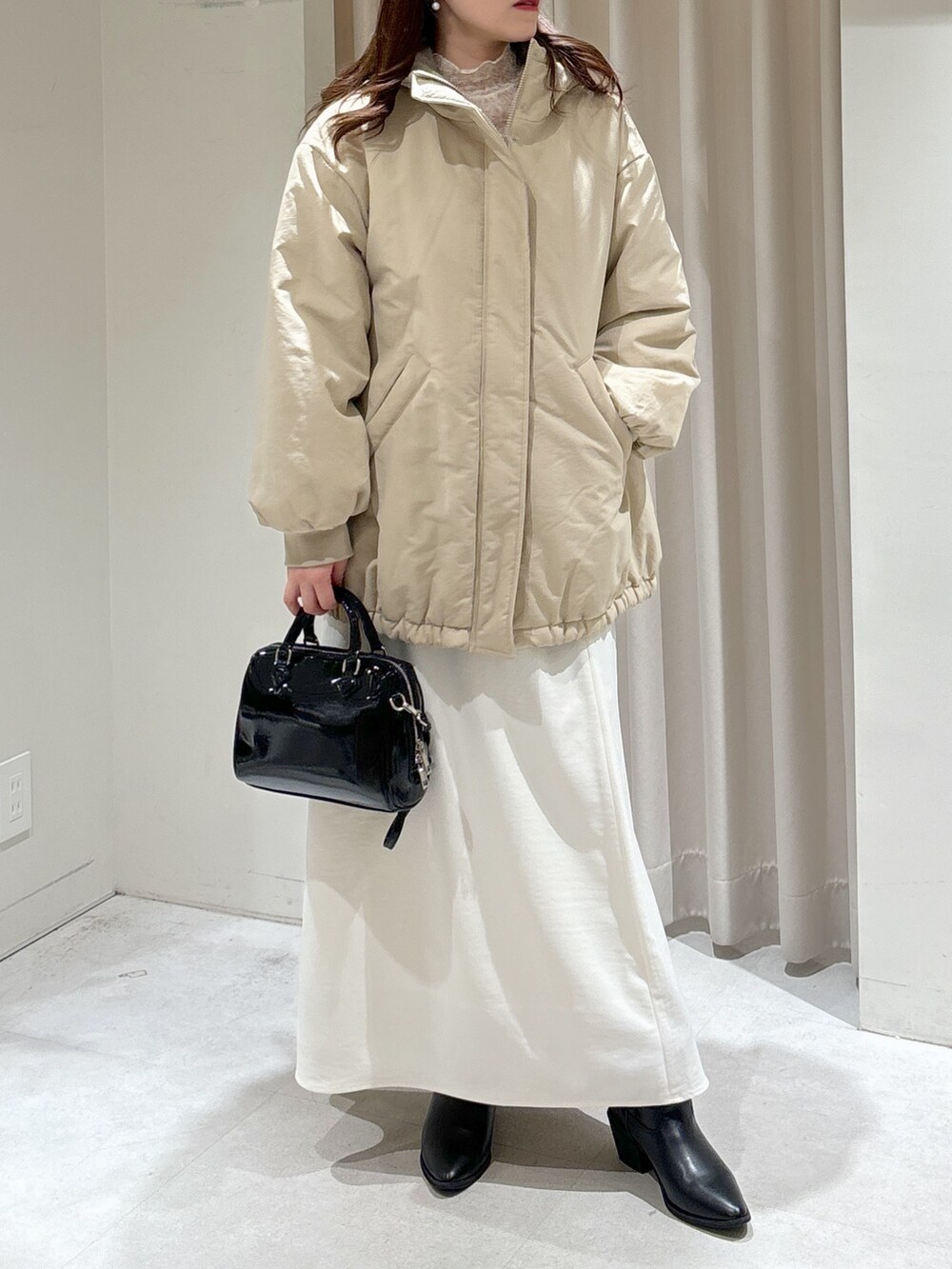 ベージュ系のブルゾン、ブラック系のショルダーバッグ、ホワイト系のスカートを着用したレディースの冬コーディネートの6枚目の写真
