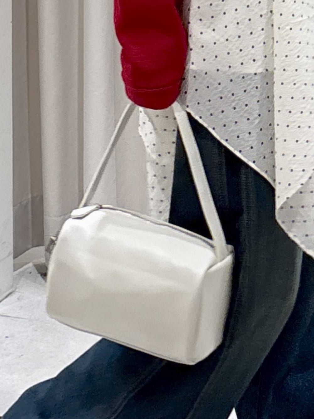 レッド系のニット/セーター、ホワイト系のワンピース、ブルー系のデニムパンツを着用したレディースの春コーディネートの7枚目の写真