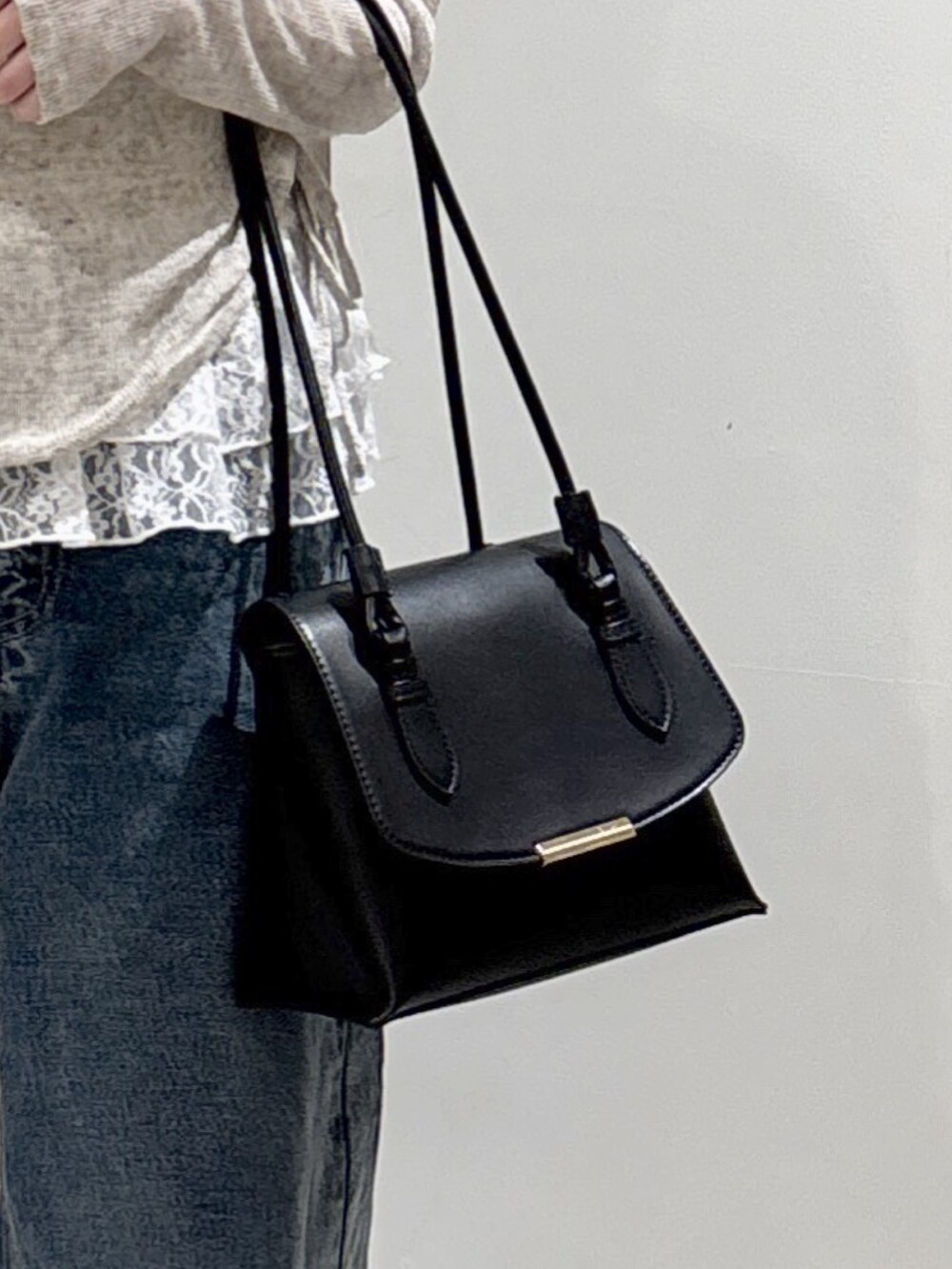 ホワイト系のTシャツ/カットソー、ブラック系のショルダーバッグ、ブルー系のデニムパンツを着用したレディースの冬コーディネートの5枚目の写真