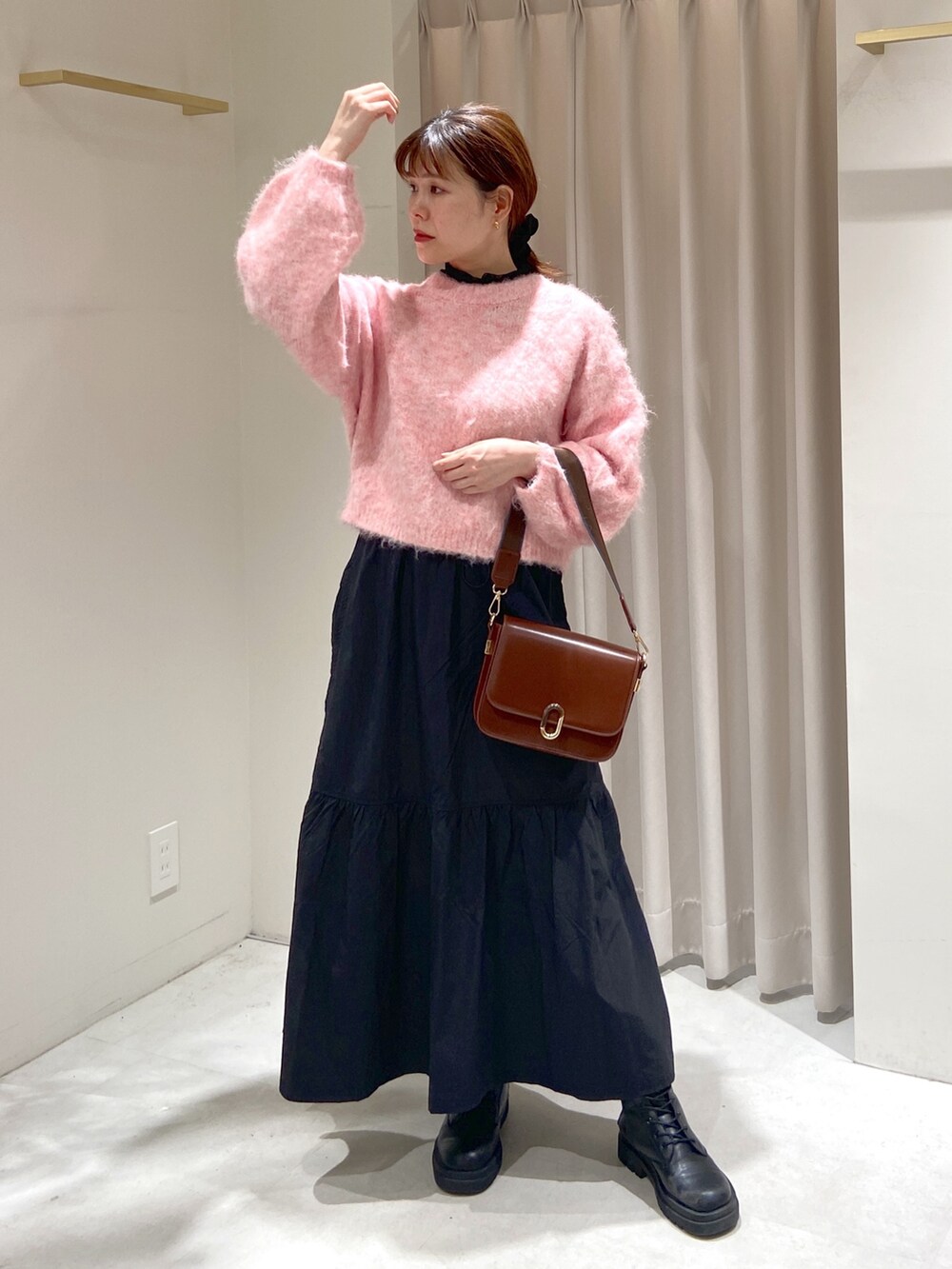 ブラック系のスカート、ブラウン系のショルダーバッグ、ブラック系のブーツを着用したレディースの冬コーディネートの5枚目の写真