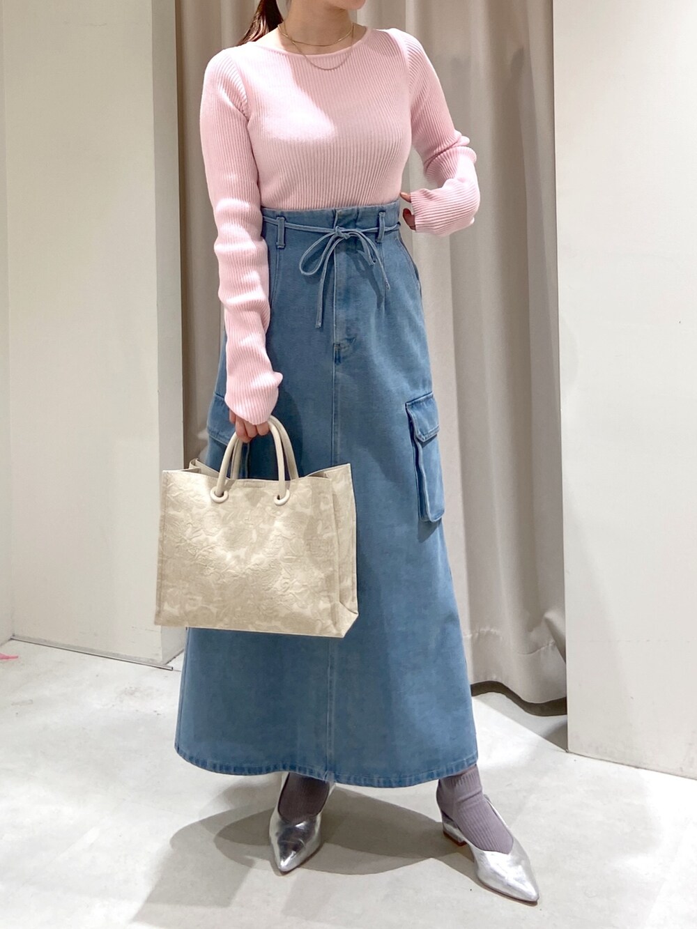 ブルー系のデニムスカート、ホワイト系のトートバッグ、シルバー系のパンプスを着用したレディースの冬コーディネートの6枚目の写真