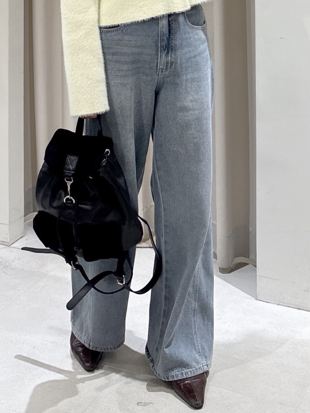 イエロー系のニット/セーター、ブルー系のデニムパンツ、ブラック系のバックパック/リュックを着用したレディースの秋コーディネートの6枚目の写真