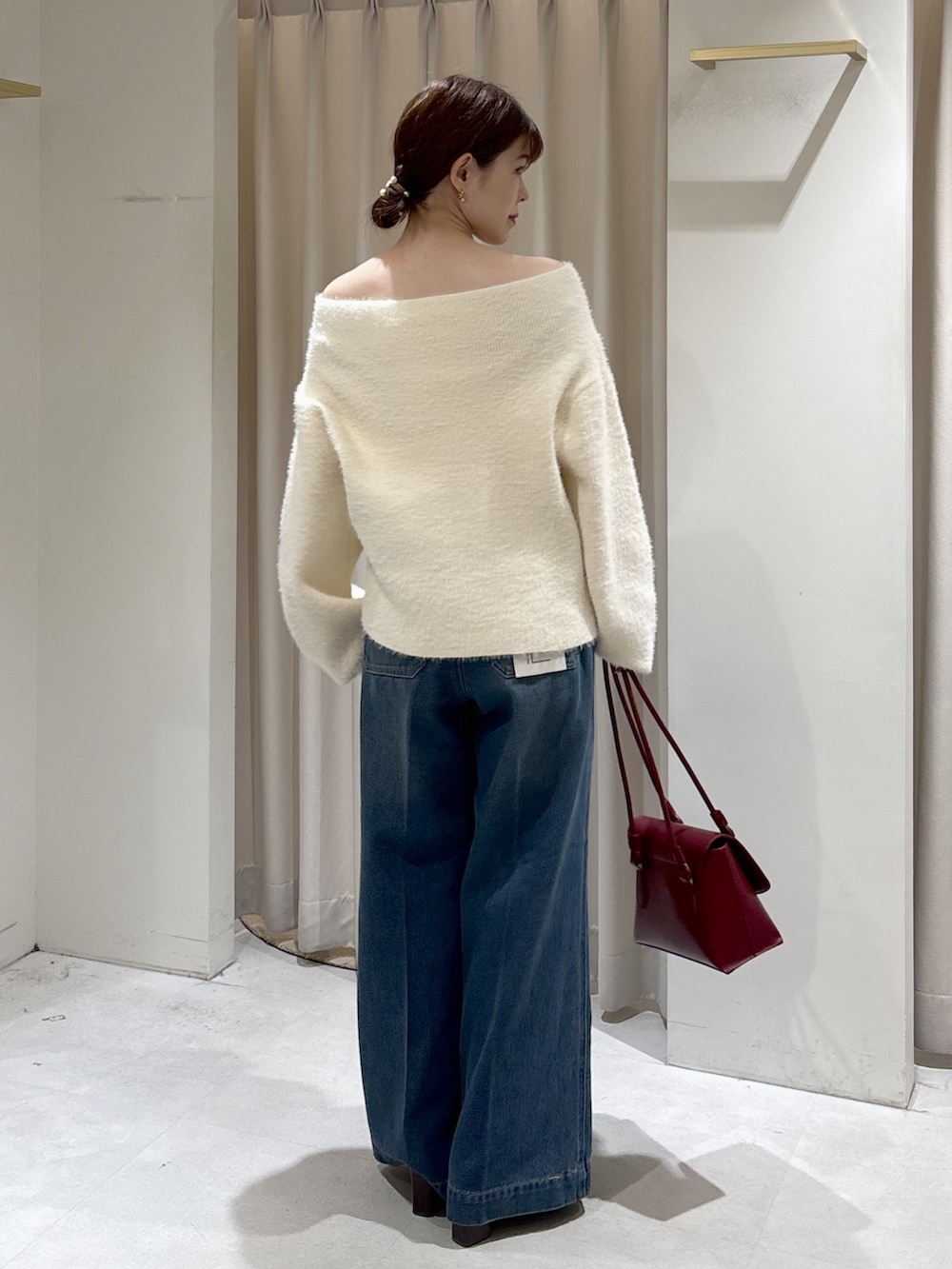 ホワイト系のニット/セーター、レッド系のトートバッグ、ブルー系のデニムパンツを着用したレディースの秋コーディネートの3枚目の写真