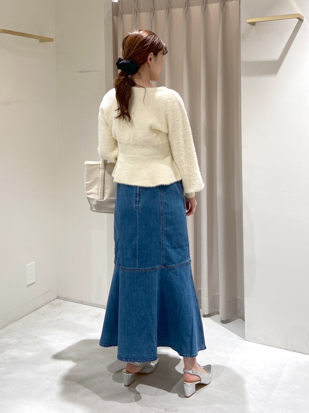 ホワイト系のカーディガン/ボレロ、ブルー系のデニムスカート、シルバー系のパンプスを着用したレディースの冬コーディネートの4枚目の写真