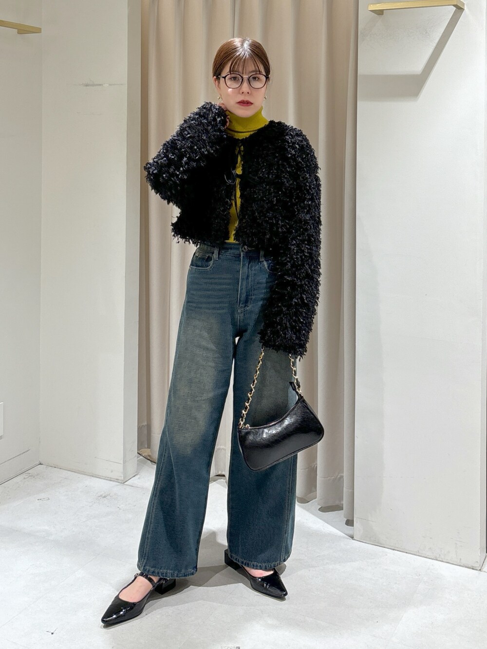 ブラック系のカーディガン/ボレロ、イエロー系のニット/セーター、ブルー系のデニムパンツを着用したレディースの秋コーディネートの2枚目の写真