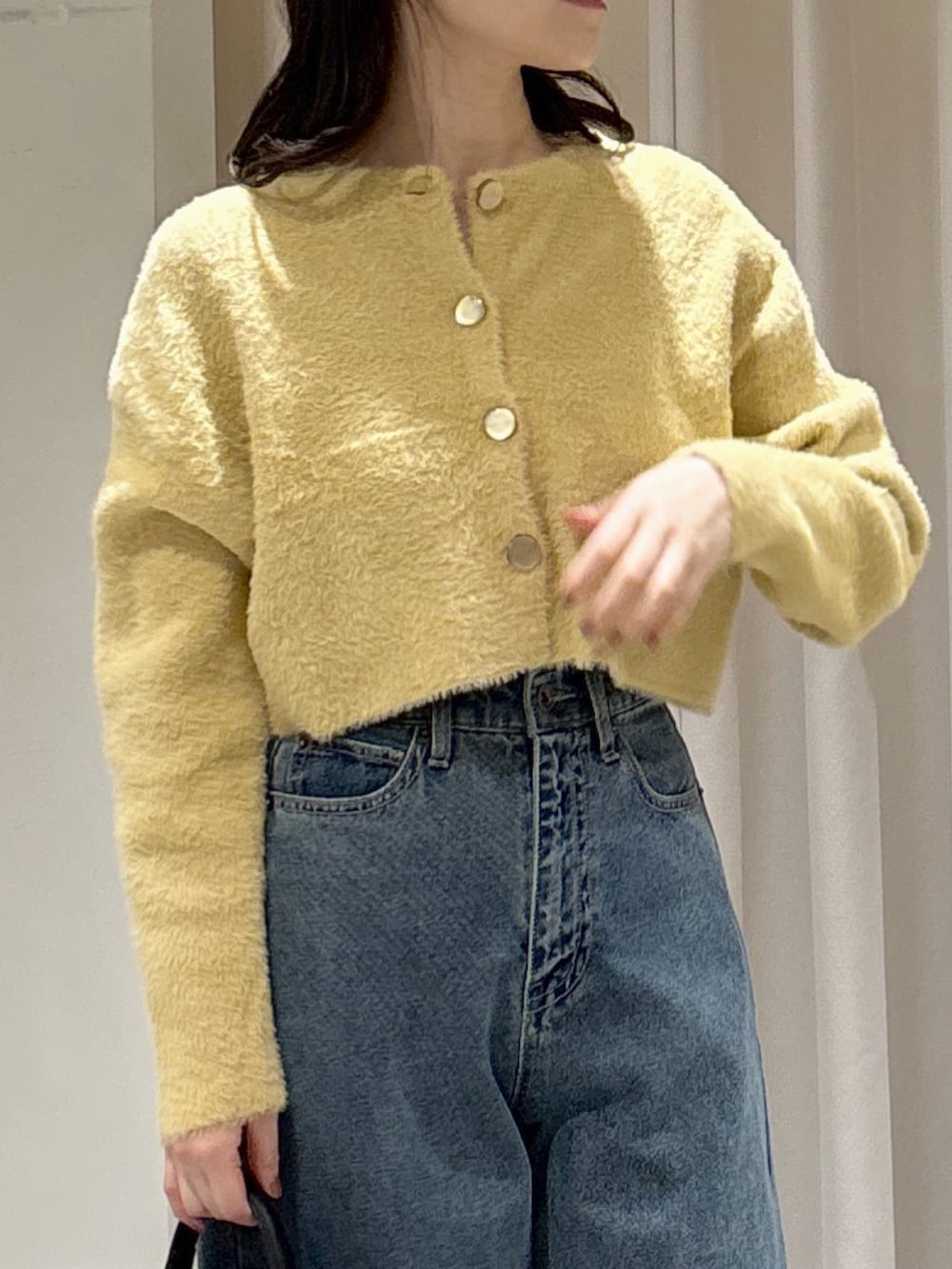 イエロー系のニット/セーター、ブラック系のトートバッグ、ブルー系のデニムパンツを着用したレディースの冬コーディネートの8枚目の写真