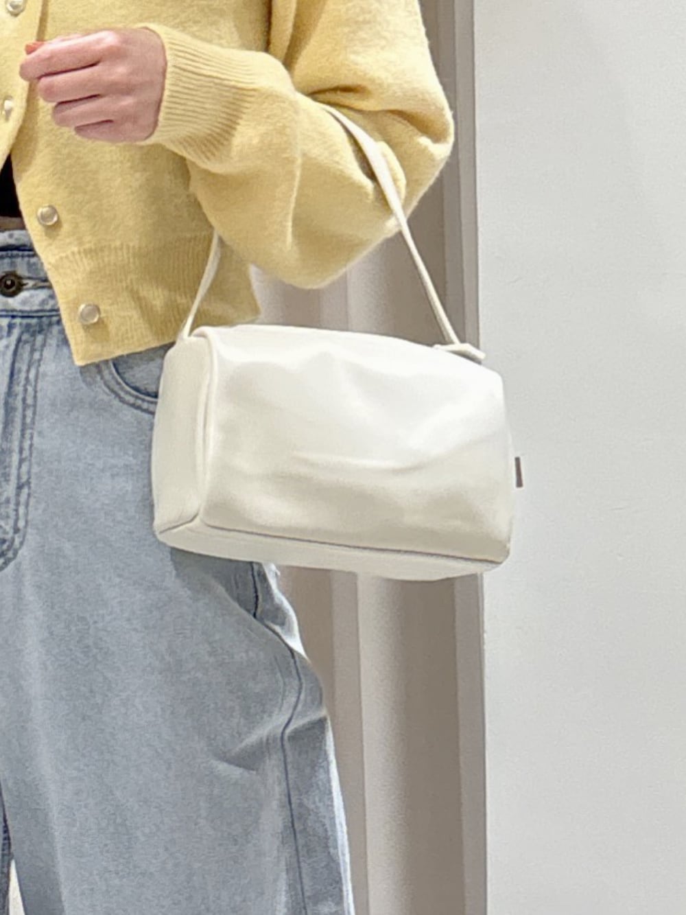 イエロー系のニット/セーター、ブラウン系のパンプス、ブルー系のデニムパンツを着用したレディースの冬コーディネートの6枚目の写真