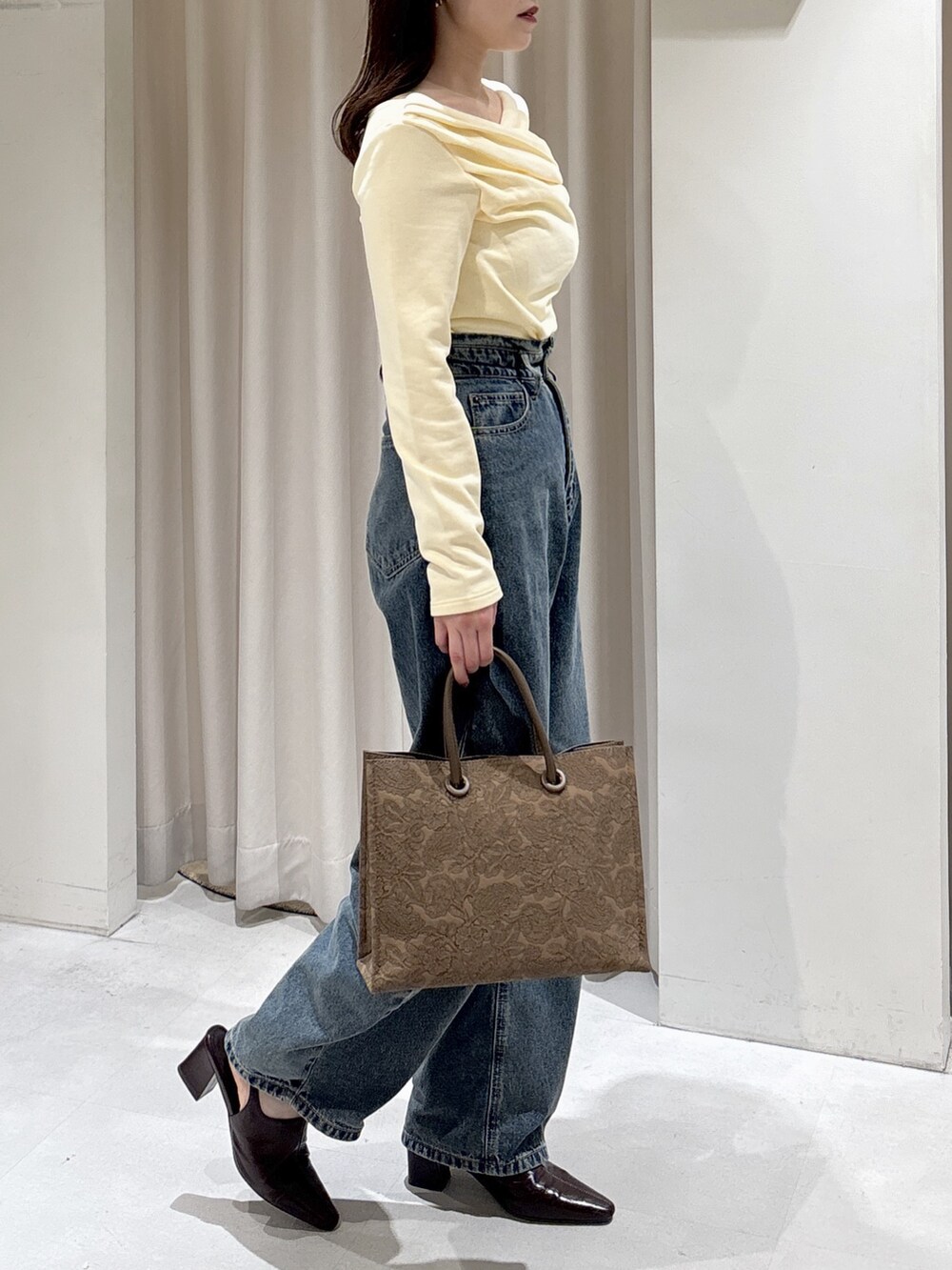 イエロー系のTシャツ/カットソー、ブルー系のデニムパンツ、ブラウン系のパンプスを着用したレディースの冬コーディネートの2枚目の写真