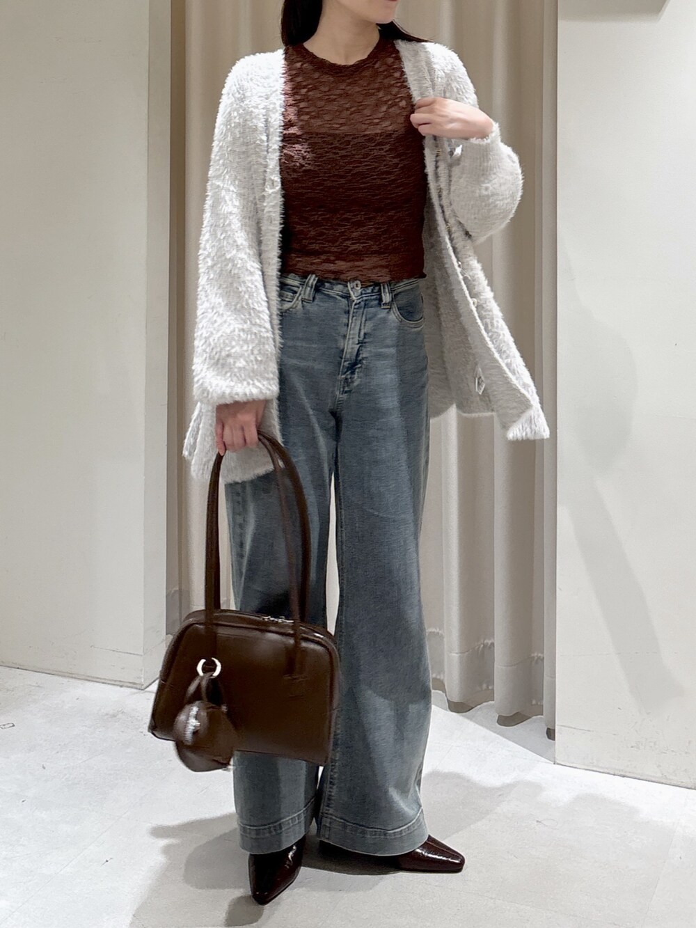 グレー系のニット/セーター、ブラウン系のTシャツ/カットソー、ブラウン系のトートバッグを着用したレディースの秋コーディネートの3枚目の写真