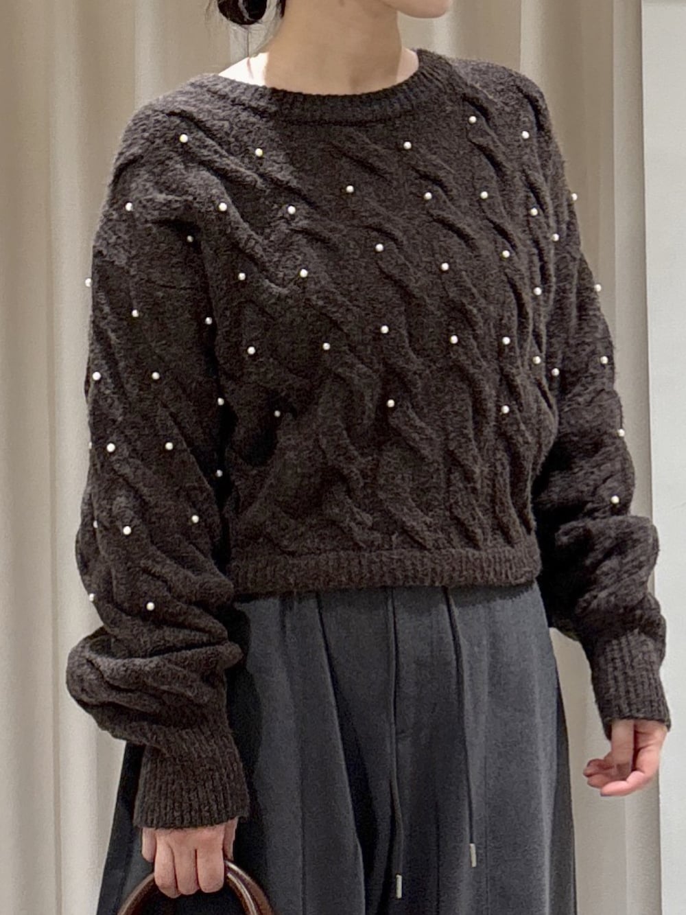 ブラウン系のニット/セーター、グレー系のその他パンツ、ブラウン系のハンドバッグを着用したレディースの冬コーディネートの2枚目の写真