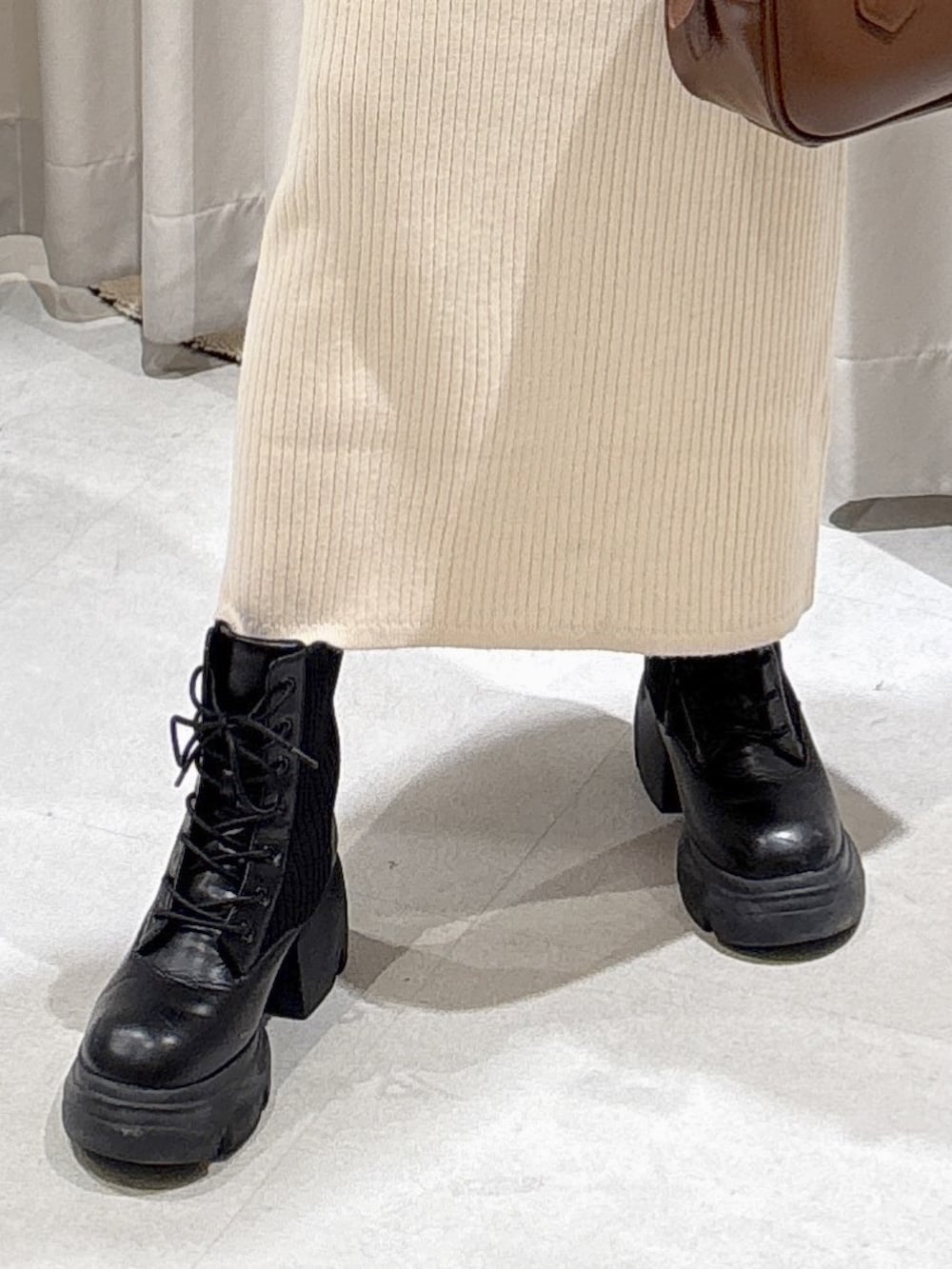 ホワイト系のワンピース、ブラウン系のハンドバッグ、ブラック系のブーツを着用したレディースの冬コーディネートの5枚目の写真