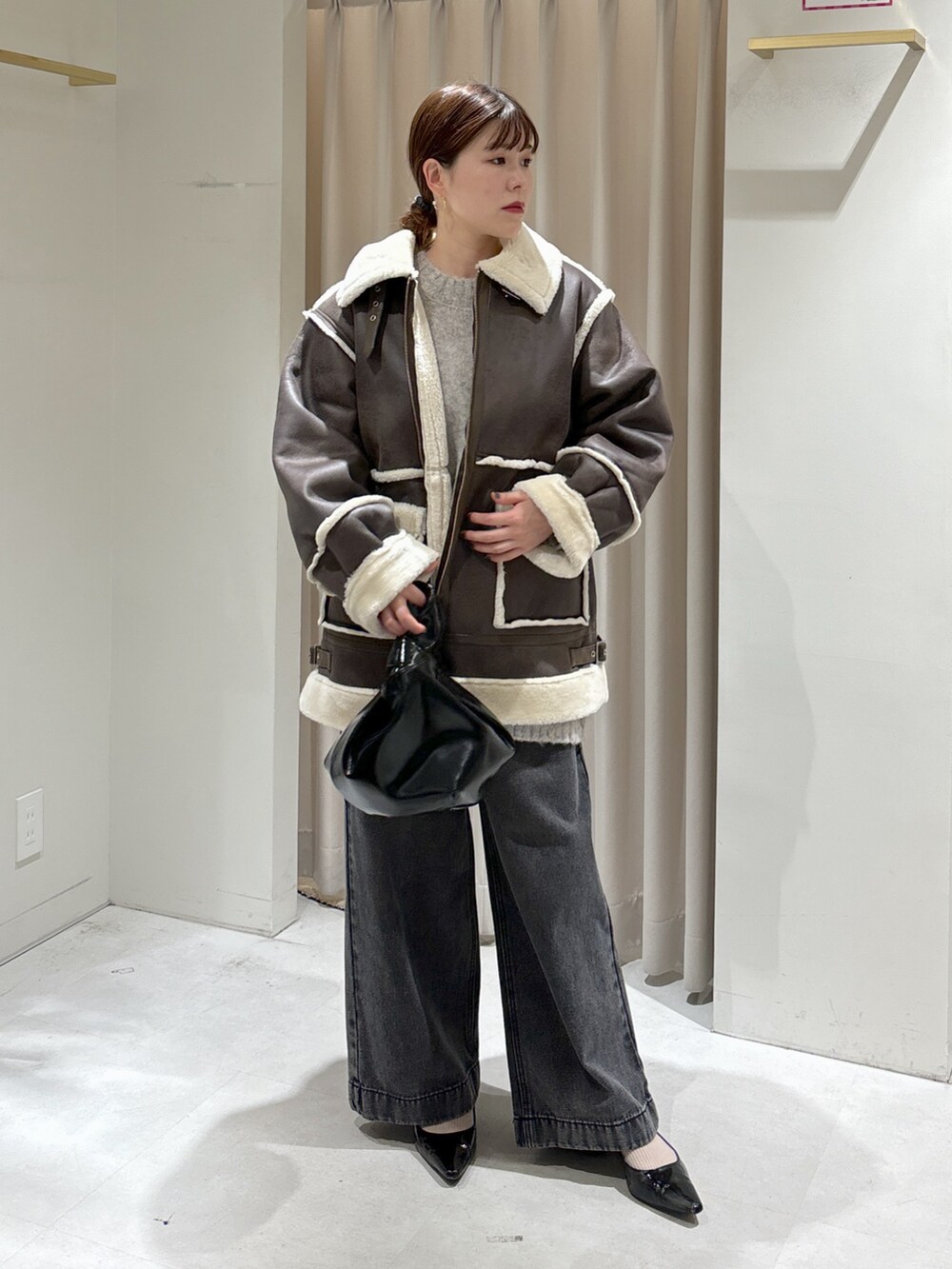 ブラウン系のブルゾン、ブラック系のデニムパンツ、ブラック系のハンドバッグを着用したレディースの秋コーディネートの2枚目の写真