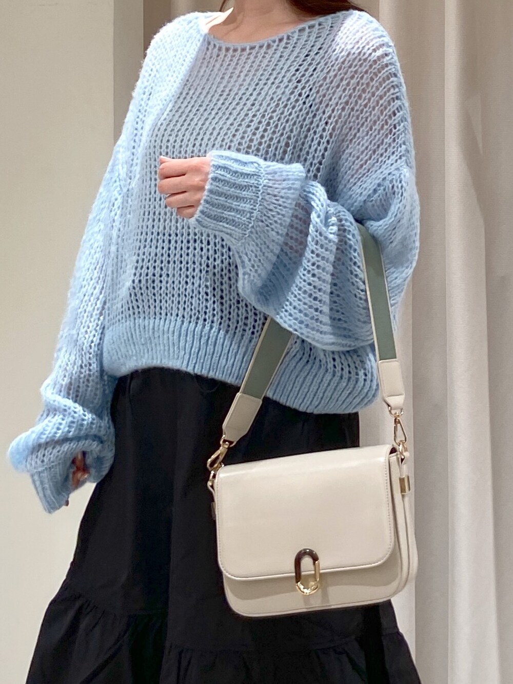 ブルー系のニット/セーター、ホワイト系のショルダーバッグ、ブラック系のスカートを着用したレディースの冬コーディネートの4枚目の写真