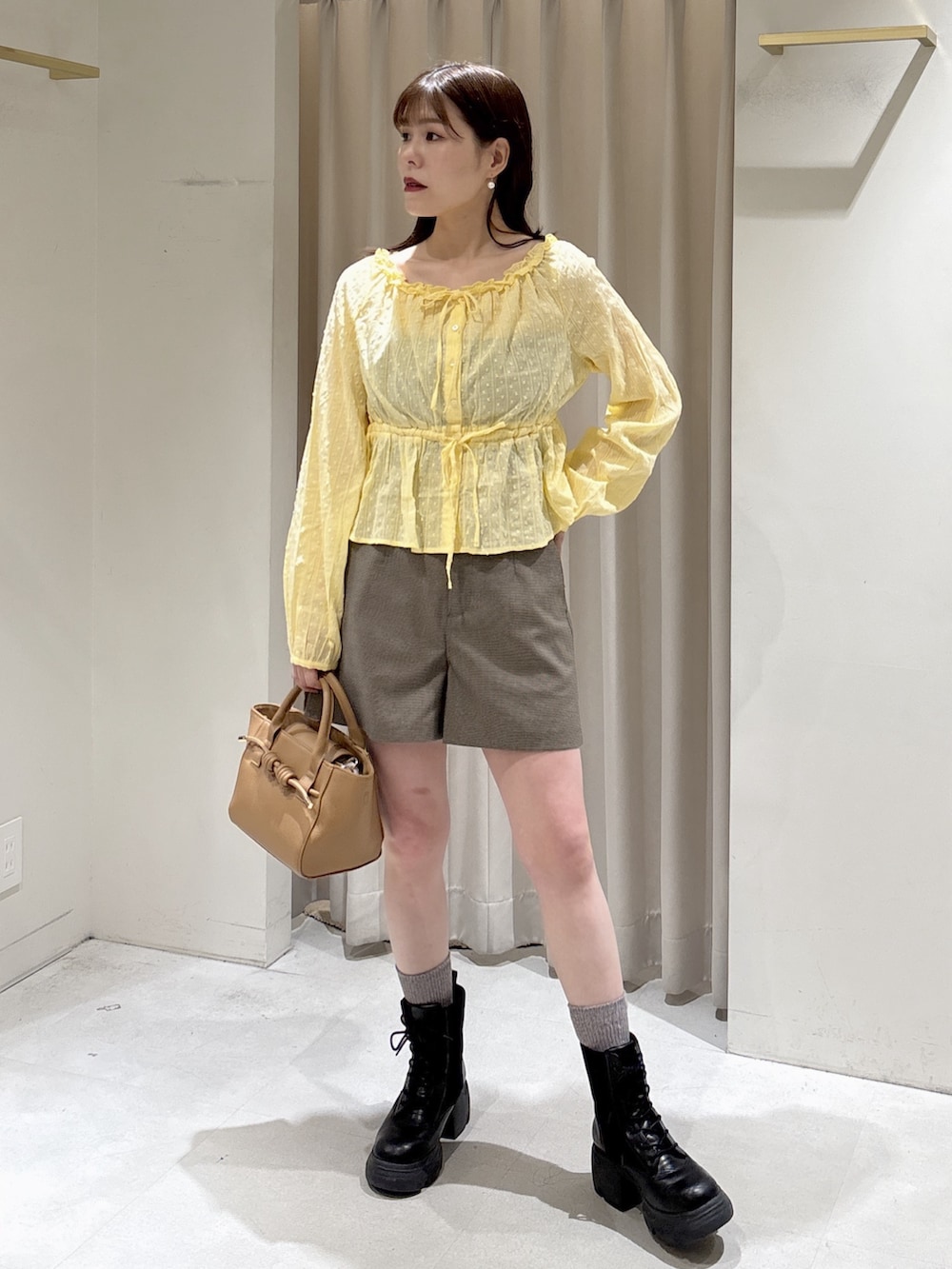 イエロー系のシャツ/ブラウス、ブラック系のブーツ、ベージュ系のハンドバッグを着用したレディースの冬コーディネートの6枚目の写真