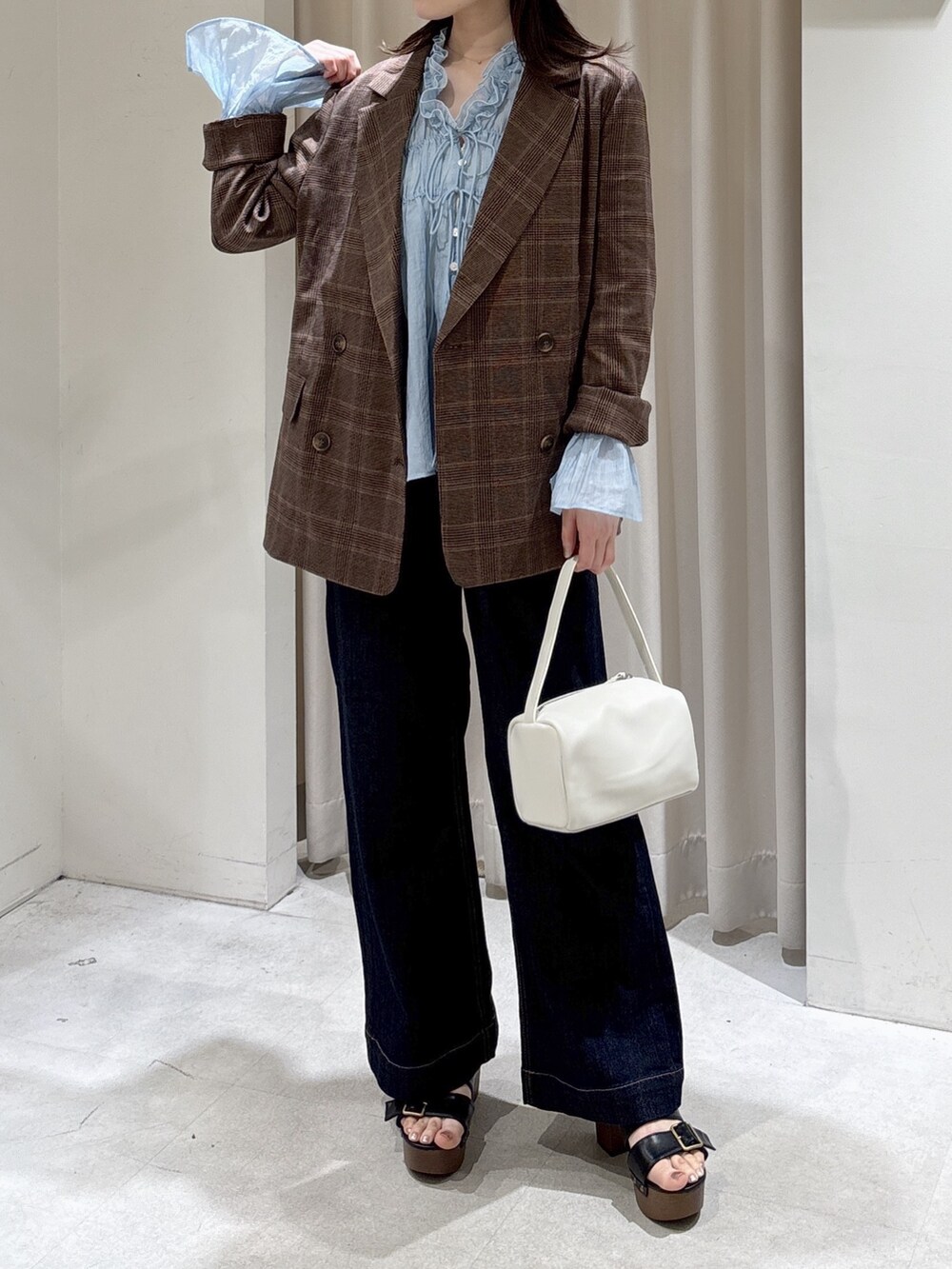 ブラウン系のテーラードジャケット、ホワイト系のハンドバッグ、ブルー系のデニムパンツを着用したレディースの春コーディネートの2枚目の写真