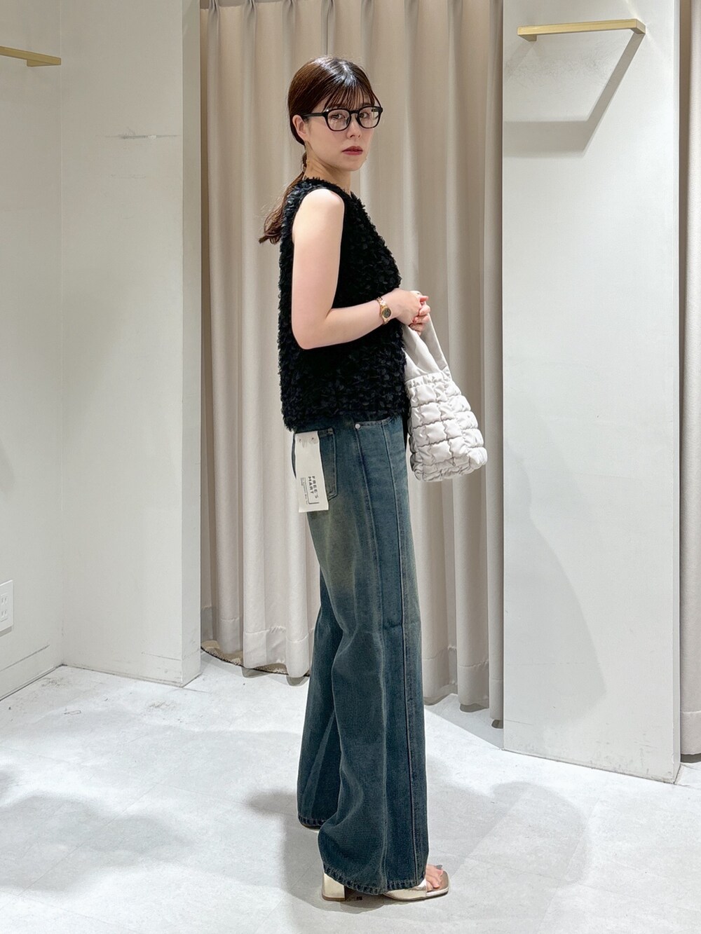 ブラック系のシャツ/ブラウス、ホワイト系のハンドバッグ、ブルー系のデニムパンツを着用したレディースの秋コーディネートの2枚目の写真