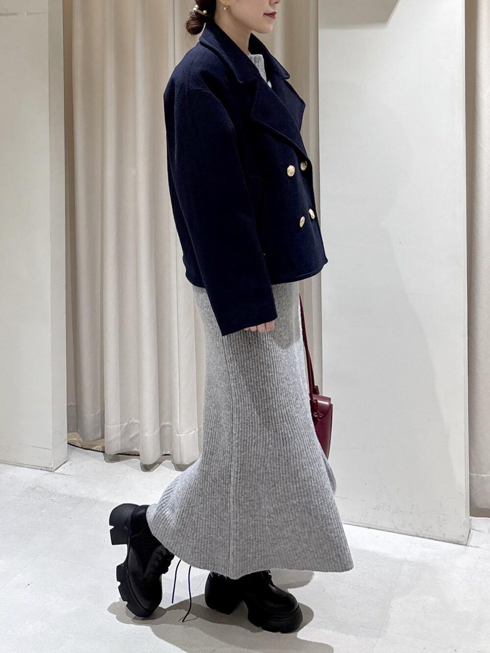 ブルー系のピーコート、レッド系のショルダーバッグ、グレー系のワンピースを着用したレディースの秋コーディネートの3枚目の写真