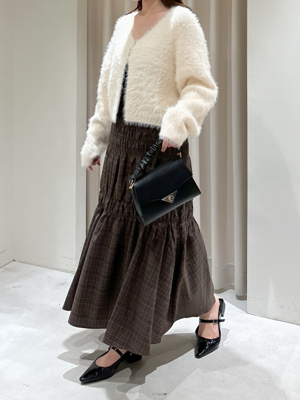 ホワイト系のカーディガン/ボレロ、ブラック系のキャミソール、ブラック系のショルダーバッグを着用したレディースの秋コーディネートの2枚目の写真