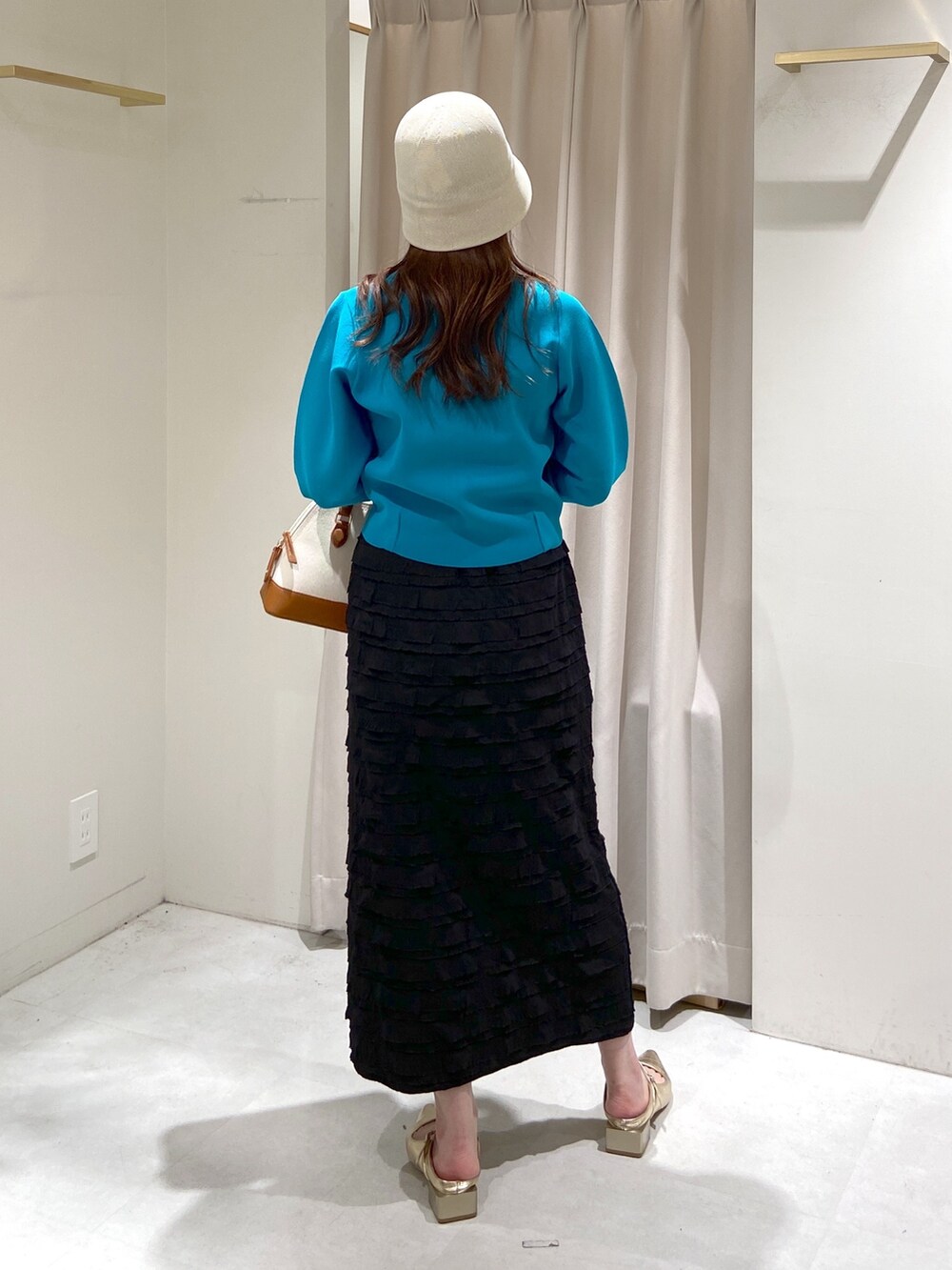 ブラック系のスカート、ブルー系のニット/セーター、ブラウン系のショルダーバッグを着用したレディースの春コーディネートの7枚目の写真